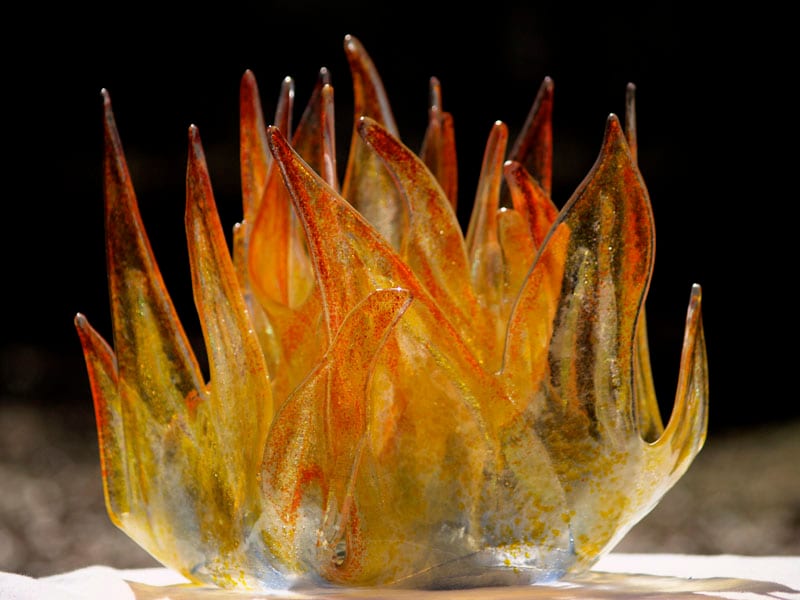 A kiln-formed fused glass sculpture with layered color and texture against a neutral background