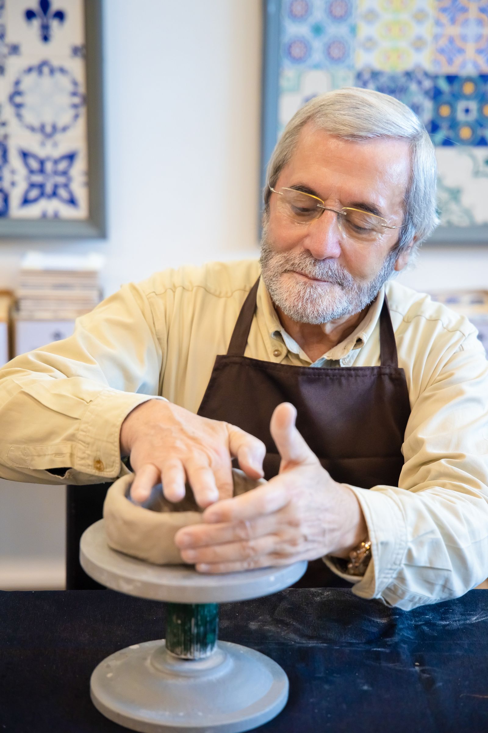 Potter loading ceramic bisqueware into a top-loading kiln in a home pottery studio