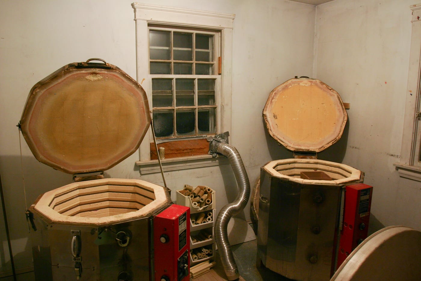 Two top-loading electric pottery kilns standing side by side in a home ceramics studio