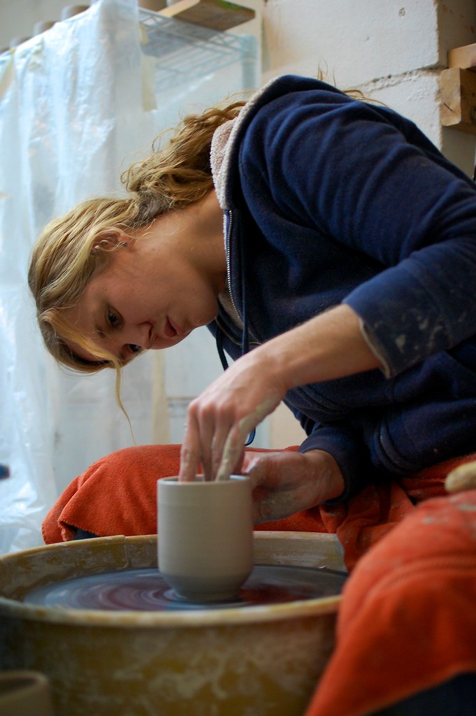 Potter centering a large mound of clay on a floor pottery wheel in a home studio