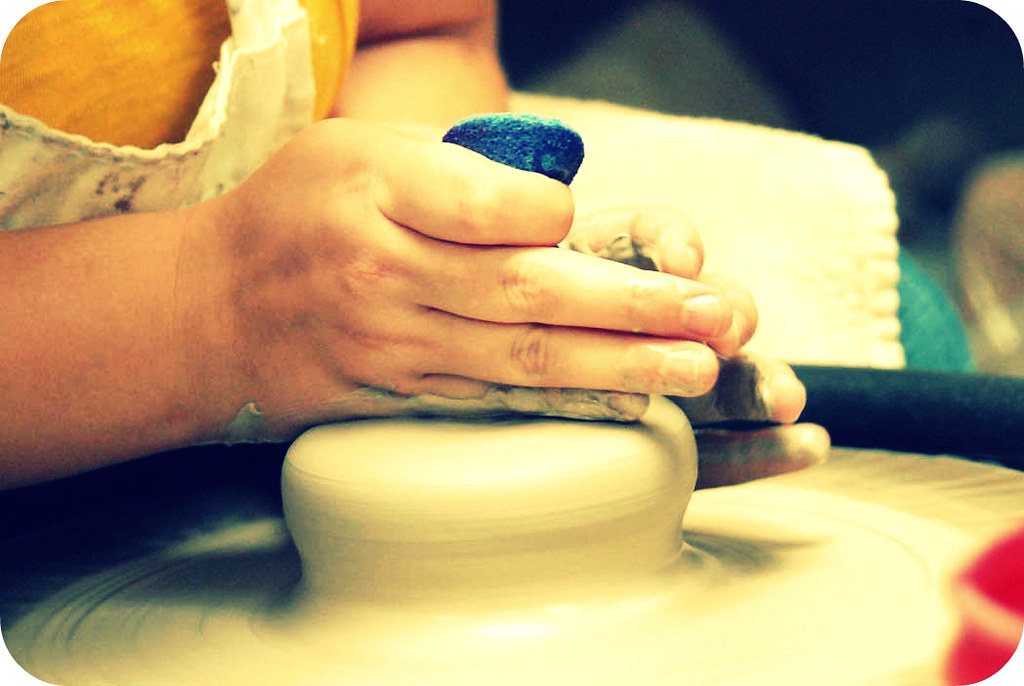 Potter guiding clay up into a cylinder on a wheel head