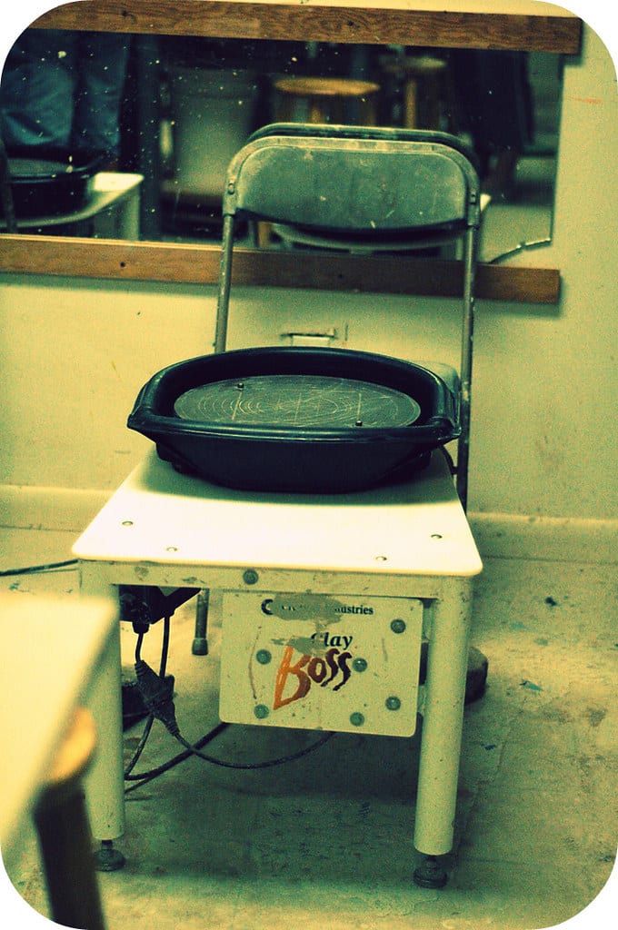 A compact tabletop pottery wheel set up on a stand