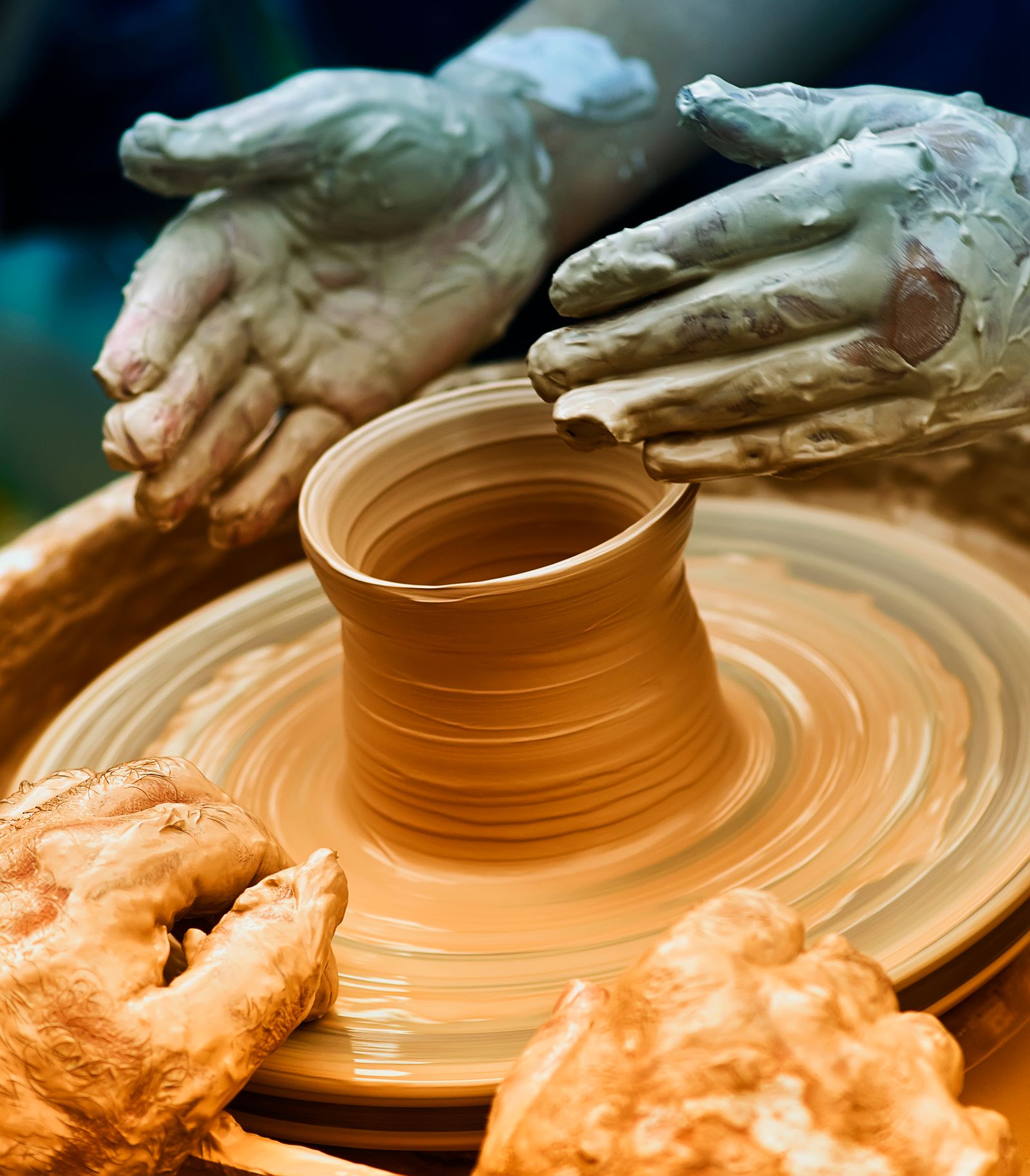 Hands shaping clay on a spinning pottery wheel