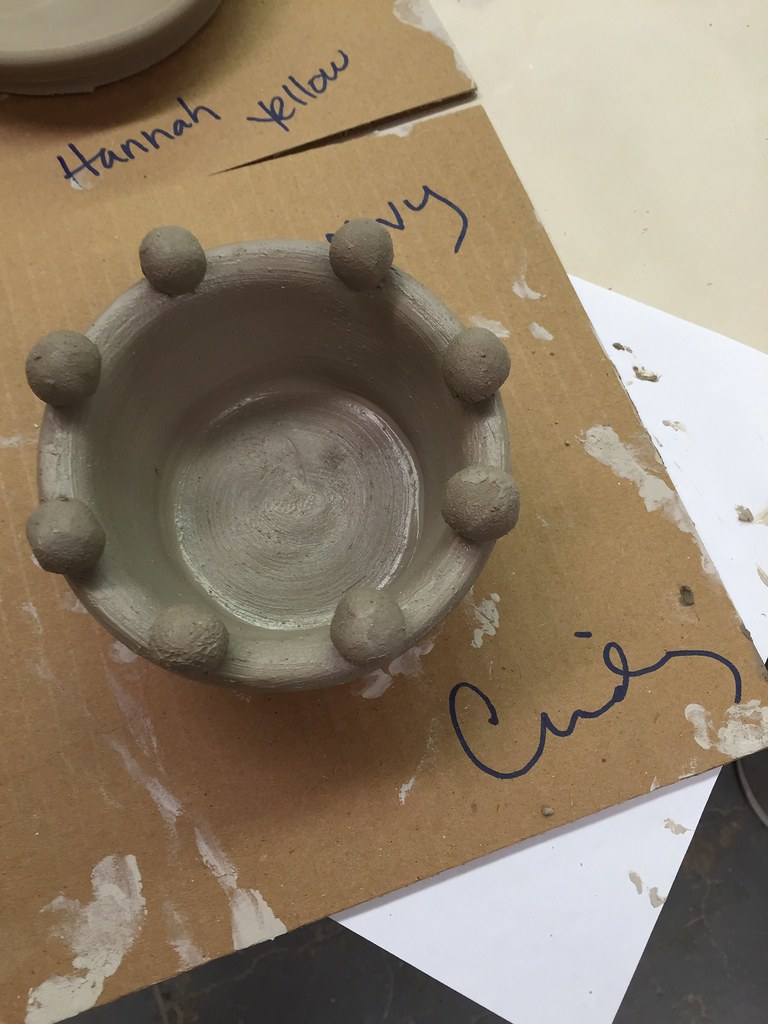 Community ceramics studio with multiple pottery wheels and students throwing
